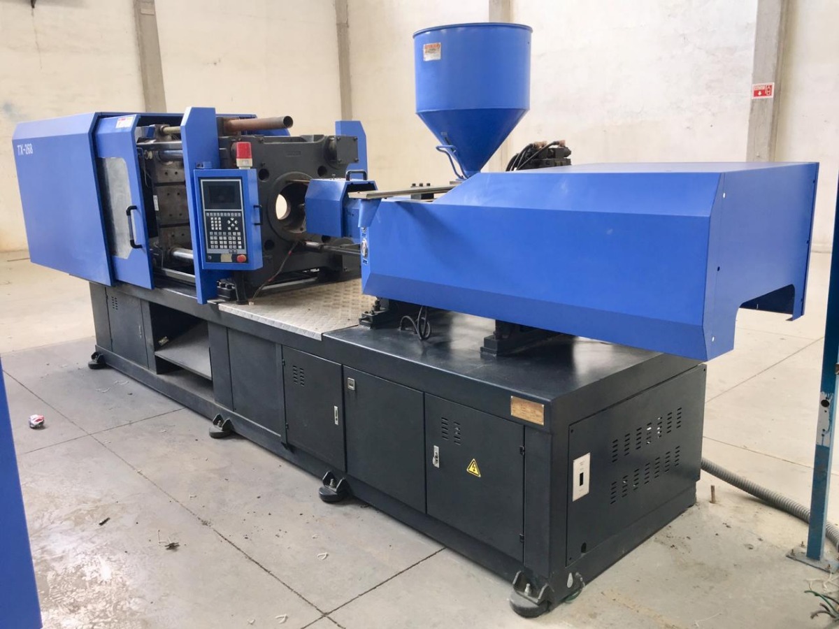 Máquina de inyección de plástico en planta industrial Equipo automatizado de inyección de plástico en funcionamiento dentro de una fábrica, alimentando el molde con polímero fundido